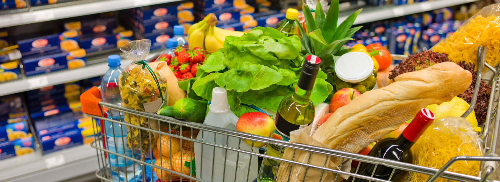 Das Bild zeigt einen vollen Einkaufswagen in einem Supermarkt.