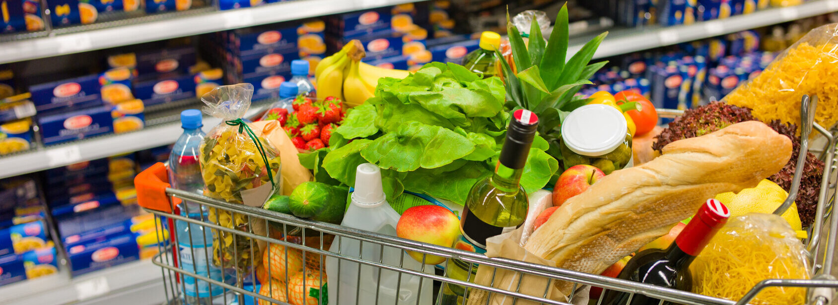 Das Bild zeigt einen vollen Einkaufswagen in einem Supermarkt.