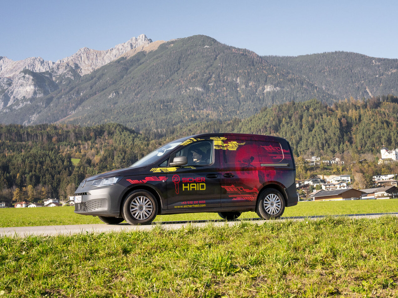 Ein Bild, das einen Firmenwagen in einer Gebirgsszenerie darstellt.