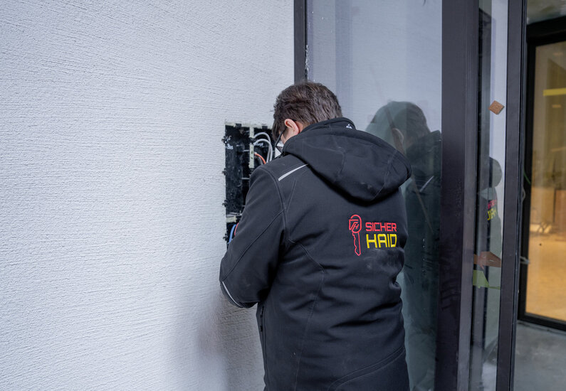 Sicherhaid Das Bild zeigt einen MA bei der Montage einer Gegensprechanlage.