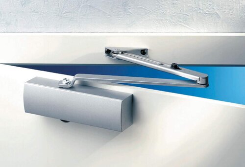 Das Bild zeigt einen automatischen Türschließer, montiert an einer Glastür.