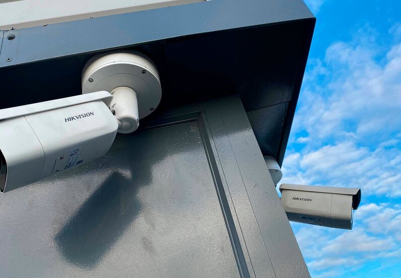 Hikvision Ein Bild, das zwei Überwachungskameras bei einem Gebäude zeigt.