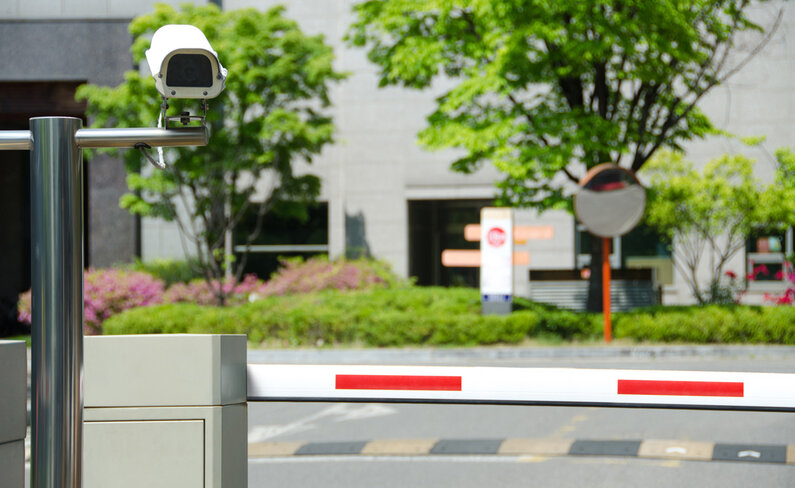 Das Bild zeigt eine ANPR-Kamera vor einem Schranken in einem Parkraum.